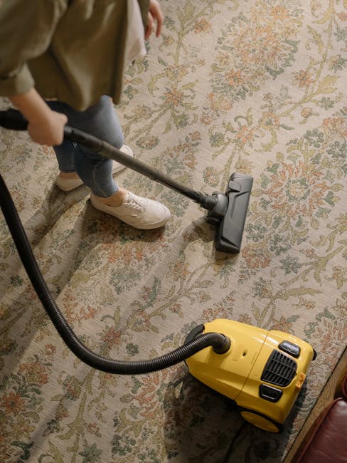 A person operating a yellow portable industrial fan for surface cleaning and ensuring thorough drying during deep cleaning processes at a residential or commercial space. The individual is holding the